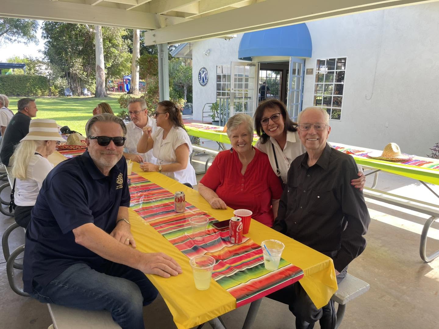 Four attendees smiling around a picnic table at a club gathering